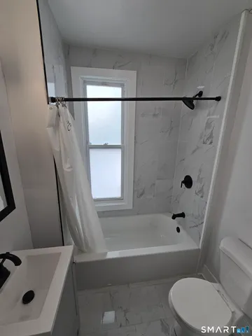 a bathroom with a bathtub a window and a shower