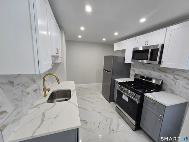 a kitchen with stainless steel appliances granite countertop a stove a sink and a microwave