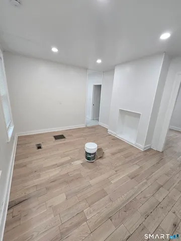 a view of an empty room with window and wooden floor