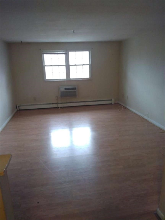 367 Hildreth Street, Unit 33 Lowell, MA 01850 - Photo 5 of 6 an empty room with wooden floor and windows