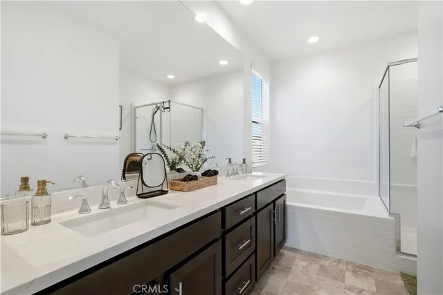 a bathroom with a sink double vanity granite tub shower and a mirror