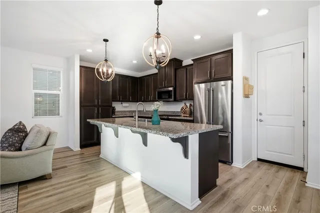 a kitchen with stainless steel appliances granite countertop a refrigerator a sink dishwasher a kitchen island with wooden cabinets and floor