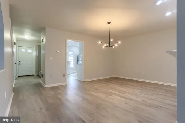an empty room with chandelier fan and windows