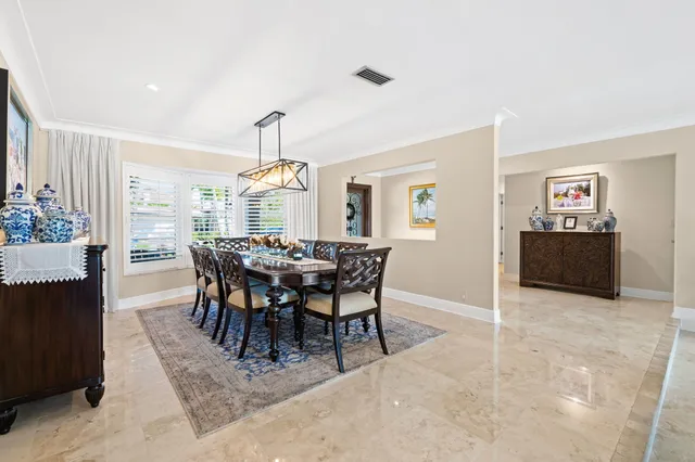 a view of a dining room and livingroom with furniture wooden floor a rug a painting and a chandelier