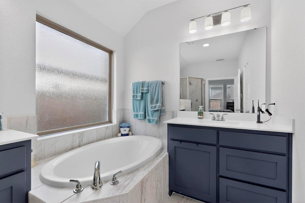 2319 Kirkstall Way Forney, TX 75126 - Photo 16 of 29 a bathroom with a bathtub a mirror a sink and vanity