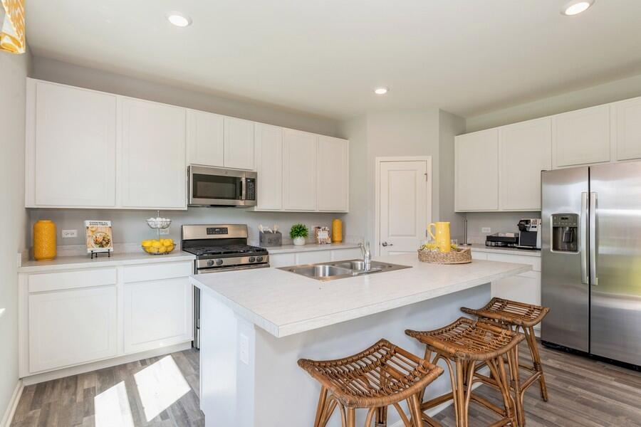 11290 Green Place Winfield, IN 46307 - Photo 14 of 27 a kitchen with a sink a stove a refrigerator and chairs