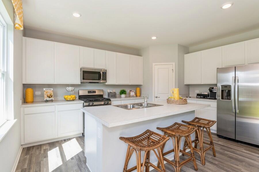 11290 Green Place Winfield, IN 46307 - Photo 17 of 27 a kitchen with stainless steel appliances a stove a sink a refrigerator white cabinets and a refrigerator