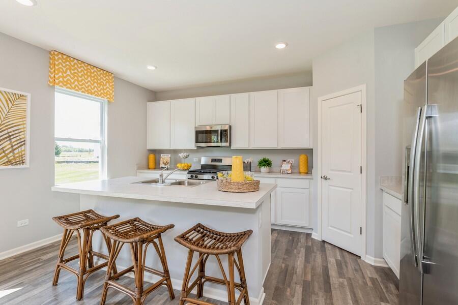 11290 Green Place Winfield, IN 46307 - Photo 2 of 27 a kitchen with stainless steel appliances granite countertop a refrigerator a sink dishwasher a stove a dining table and chairs with wooden floor