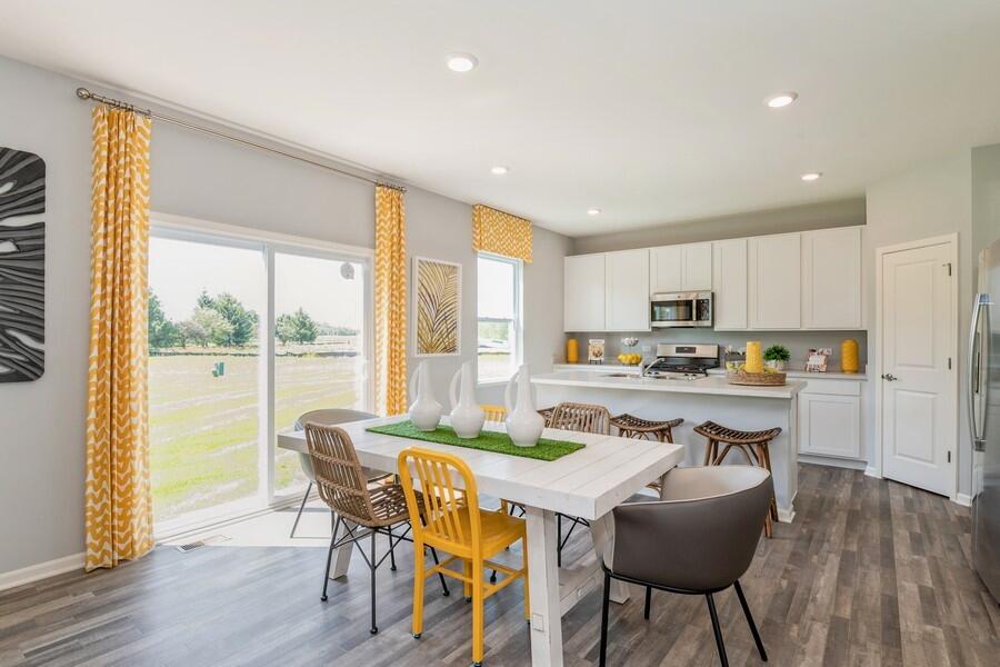 11290 Green Place Winfield, IN 46307 - Photo 3 of 27 a dining room with stainless steel appliances granite countertop a stove a refrigerator a microwave a stove and white cabinets with wooden floor