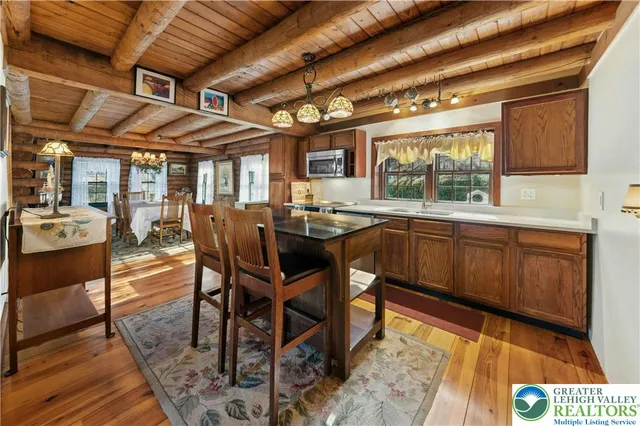 a dining hall with stainless steel appliances granite countertop a sink a stove a table and chairs