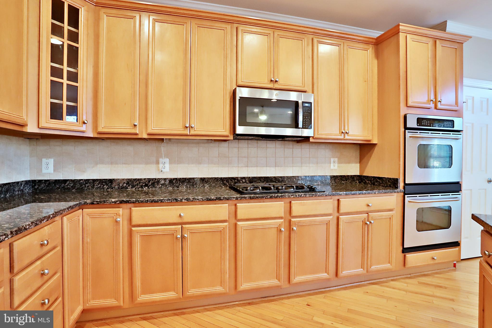 135 Fortnightly Boulevard Herndon, VA 20170 - Photo 6 of 29 a kitchen with stainless steel appliances granite countertop a stove a microwave and a white cabinets