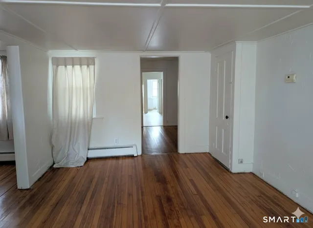a view of empty room with wooden floor