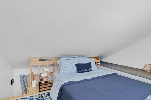 510 Spring Creek Road Providence, UT 84332 - Photo 19 of 97 Loft sleeping area featuring a built-in wooden bed frame, sloped ceiling, and an integrated carpeted bench