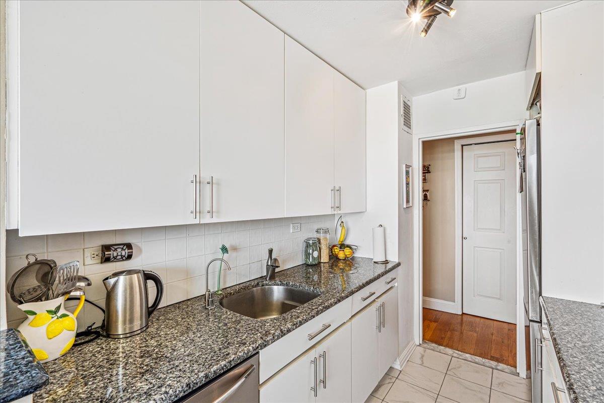 17-85 215th Street, Unit 12S Queens, NY 11360 - Photo 10 of 37 Kitchen with white cabinetry, dark stone countertops, appliances with stainless steel finishes, and decorative backsplash