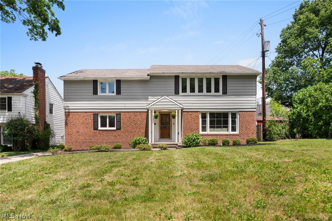 22625 Rye Road Shaker Heights, OH 44122 - Photo 2 of 38 Split-level residence featuring a brick and siding exterior, prominent front entry with a portico, multiple windows with dark shutters, and a sloped front lawn