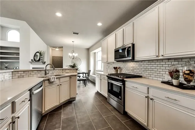 a kitchen with stainless steel appliances a sink stove top oven and cabinets