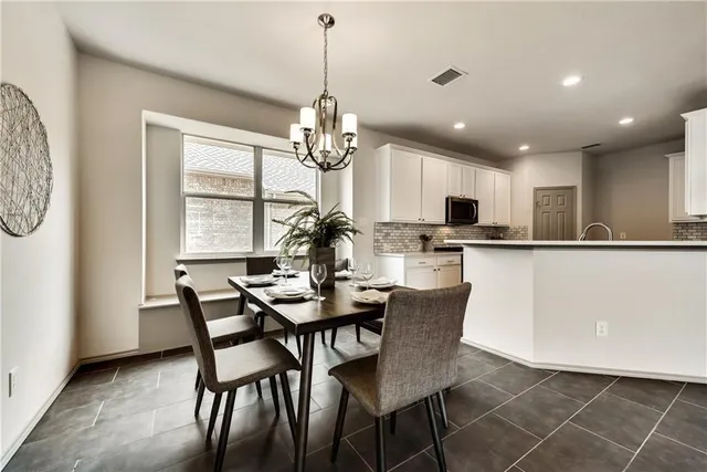 a dining room with stainless steel appliances kitchen island granite countertop a dining table chairs and granite counter tops