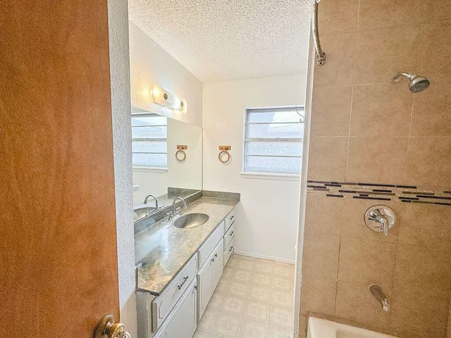 a bathroom with a granite countertop sink a mirror and shower