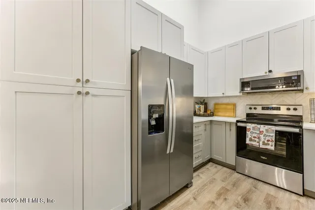 a metallic refrigerator freezer and a stove sitting inside of a kitchen
