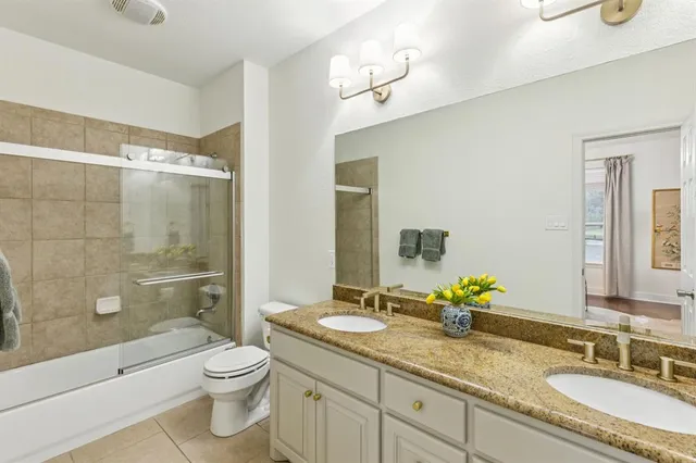 a bathroom with a granite countertop sink a toilet a mirror and shower