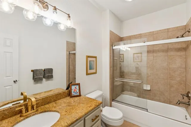 a bathroom with a granite countertop sink toilet mirror and shower