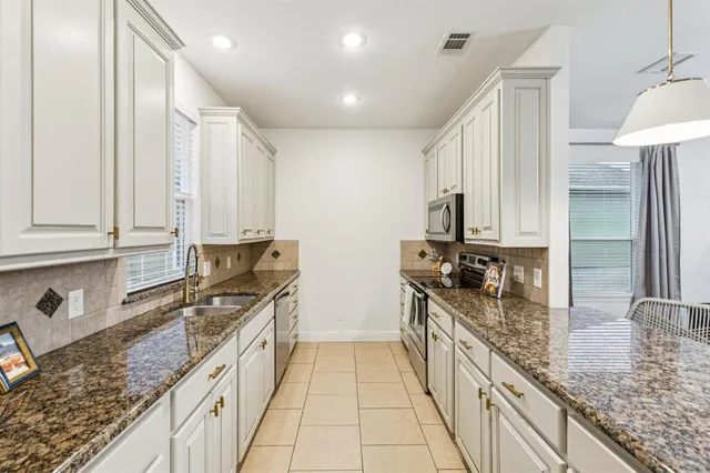 a kitchen with granite countertop a sink stove and cabinets