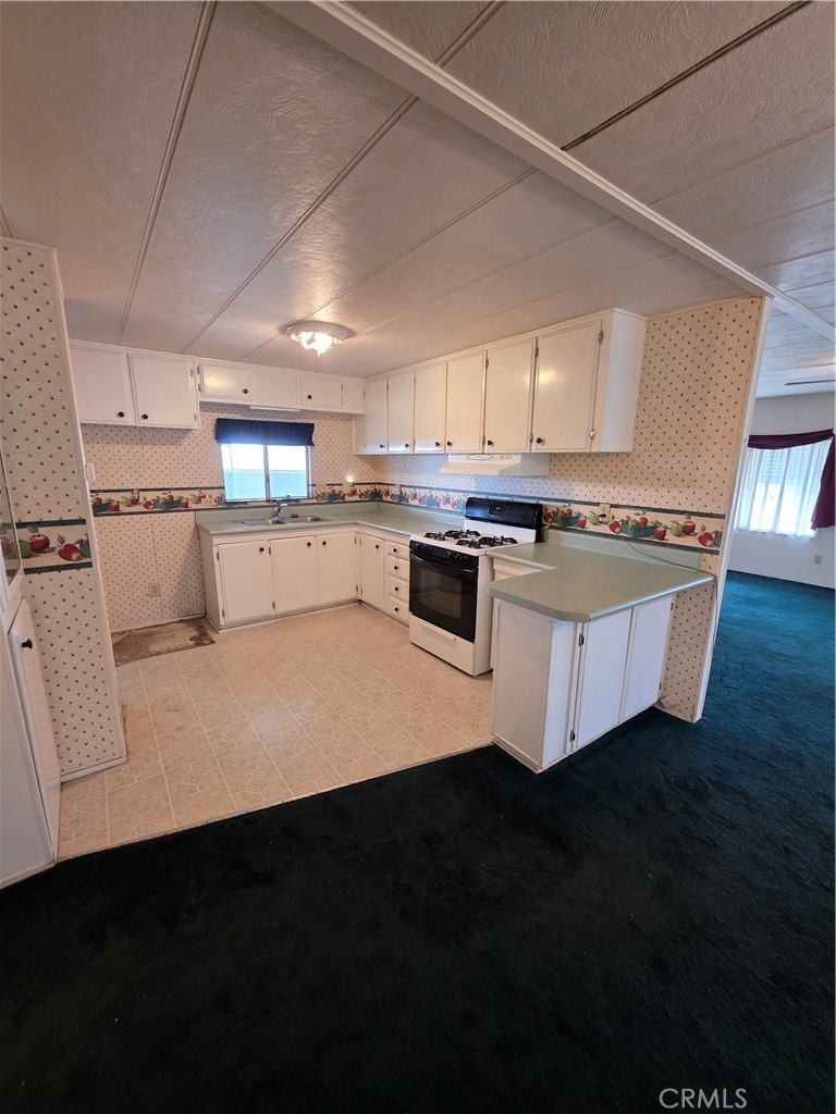 12700 2nd Street, Unit 35 Yucaipa, CA 92399 - Photo 9 of 15 a kitchen with kitchen island a stove a sink dishwasher and a refrigerator with wooden floor