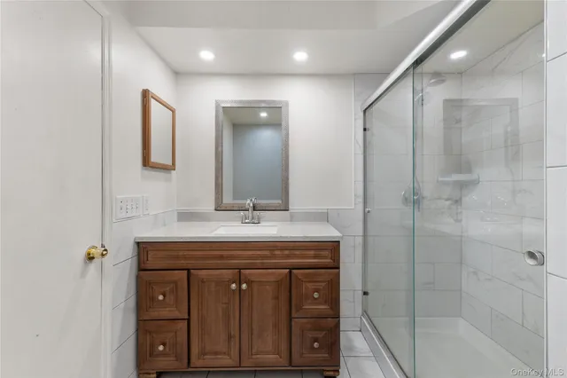 a bathroom with a granite countertop sink a mirror and shower