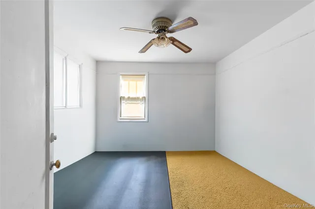 an empty room with a window and a ceiling fan