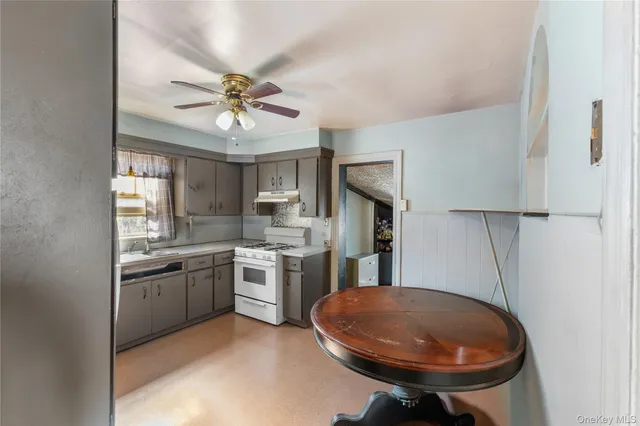 a kitchen with stainless steel appliances a sink a stove a refrigerator cabinets and a dining table