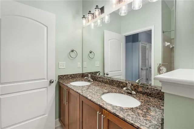 a bathroom with a granite countertop sink a mirror and a shower