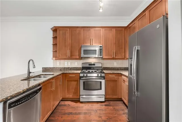 a kitchen with stainless steel appliances granite countertop a stove a sink and a refrigerator