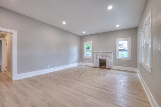 an empty room with wooden floor and fireplace
