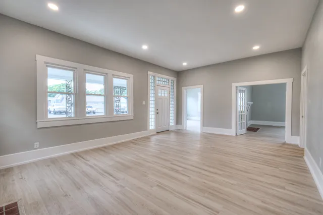 a view of an empty room with wooden floor and a window