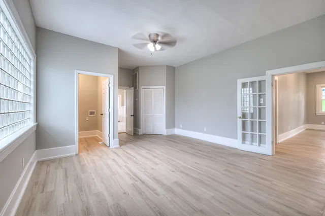 a view of empty room with wooden floor and fan