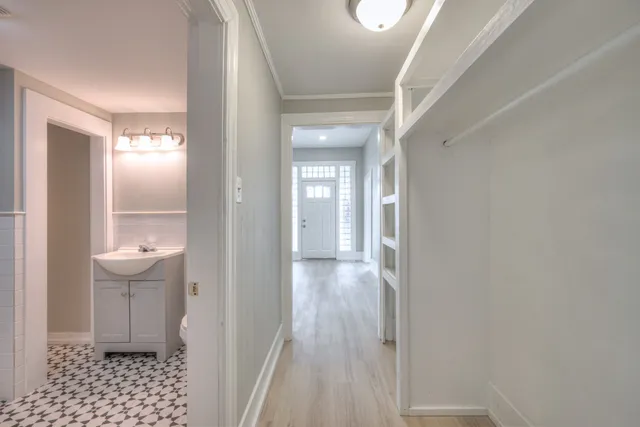 a view of a hallway with wooden floor and a bathroom
