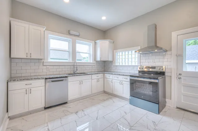 a kitchen with granite countertop white cabinets white stainless steel appliances with a sink and dishwasher