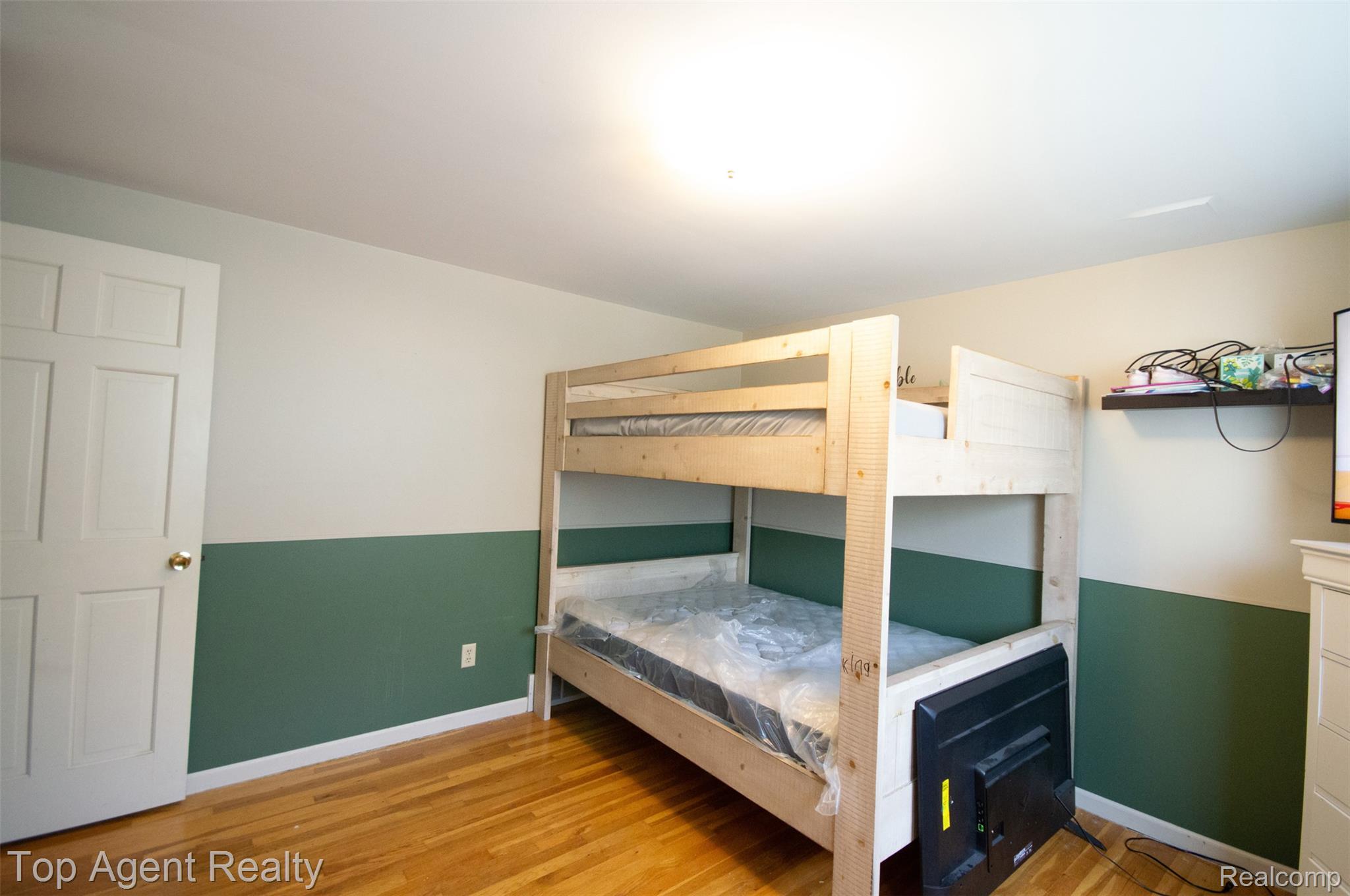 36218 Paddock Drive Clinton Township, MI 48035 - Photo 14 of 22 Room featuring light wood-finish flooring, a white six-panel door with brass hardware, and two-tone wall paint with a green wainscoting effect