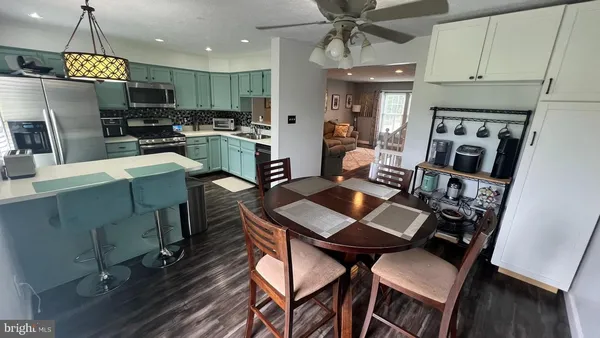 a kitchen with stainless steel appliances kitchen island granite countertop a refrigerator a stove top oven a sink dishwasher and a dining table with wooden floor