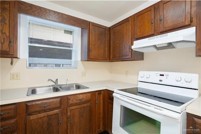 a kitchen with sink a stove and cabinets