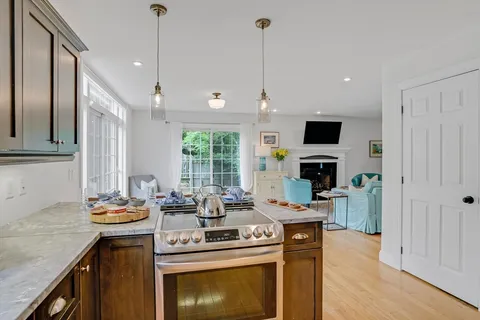 a kitchen with stainless steel appliances kitchen island granite countertop a sink a stove and a wooden floors