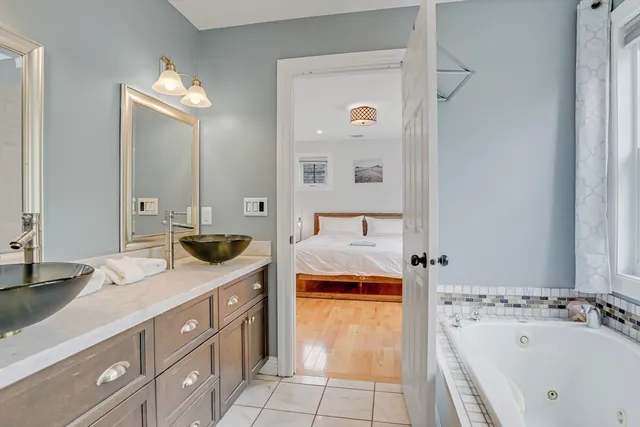 a spacious bathroom with a tub sink and mirror