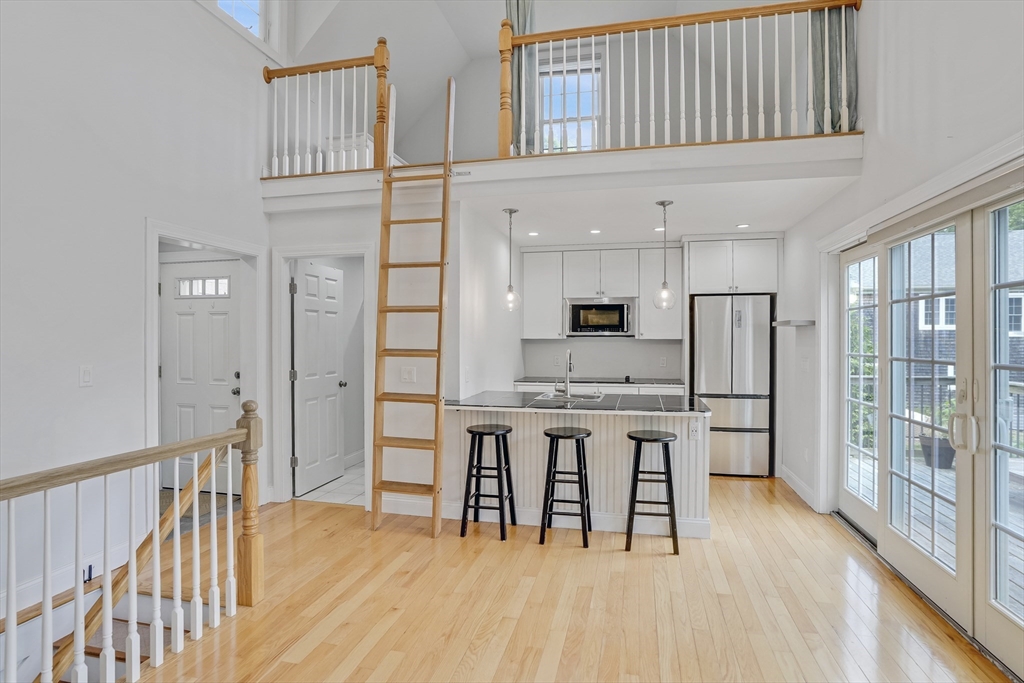 128-136 Spring Street Tisbury, MA 02568 - Photo 35 of 42 a open kitchen with stainless steel appliances granite countertop a stove top oven a refrigerator a dining table and chairs with wooden floor