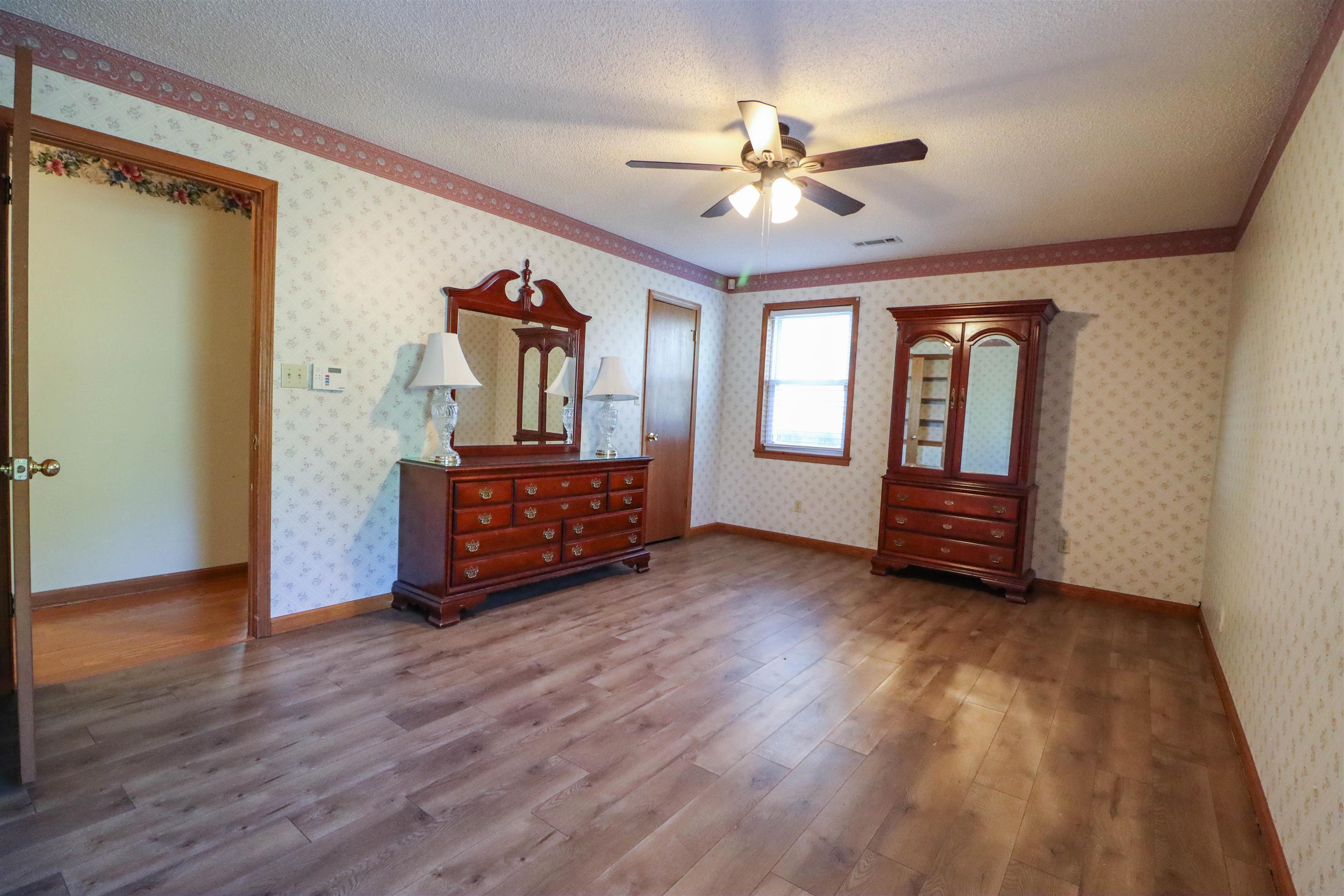 5551 Asbury Glimp Road Ripley, TN 38063 - Photo 21 of 28 a view of a livingroom with wooden floor and ceiling fan