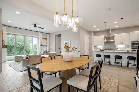 a kitchen with stainless steel appliances a dining table chairs sink refrigerator and microwave