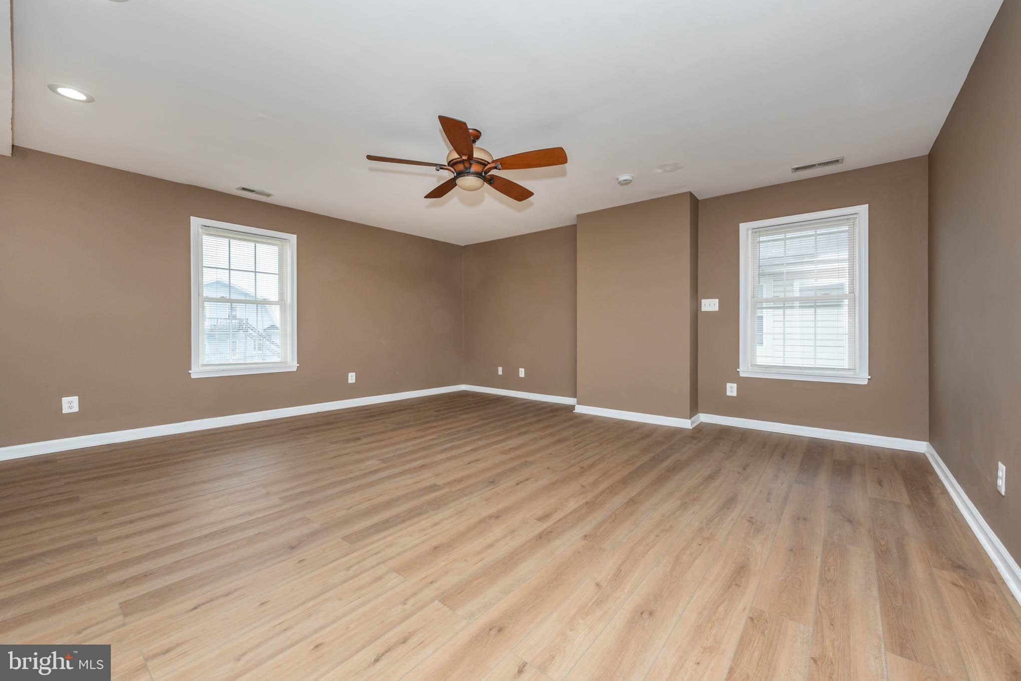 4021 Barrington Road Baltimore, MD 21207 - Photo 25 of 50 an empty room with wooden floor ceiling fan and windows