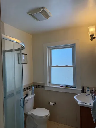 a bathroom with a toilet sink a mirror and window