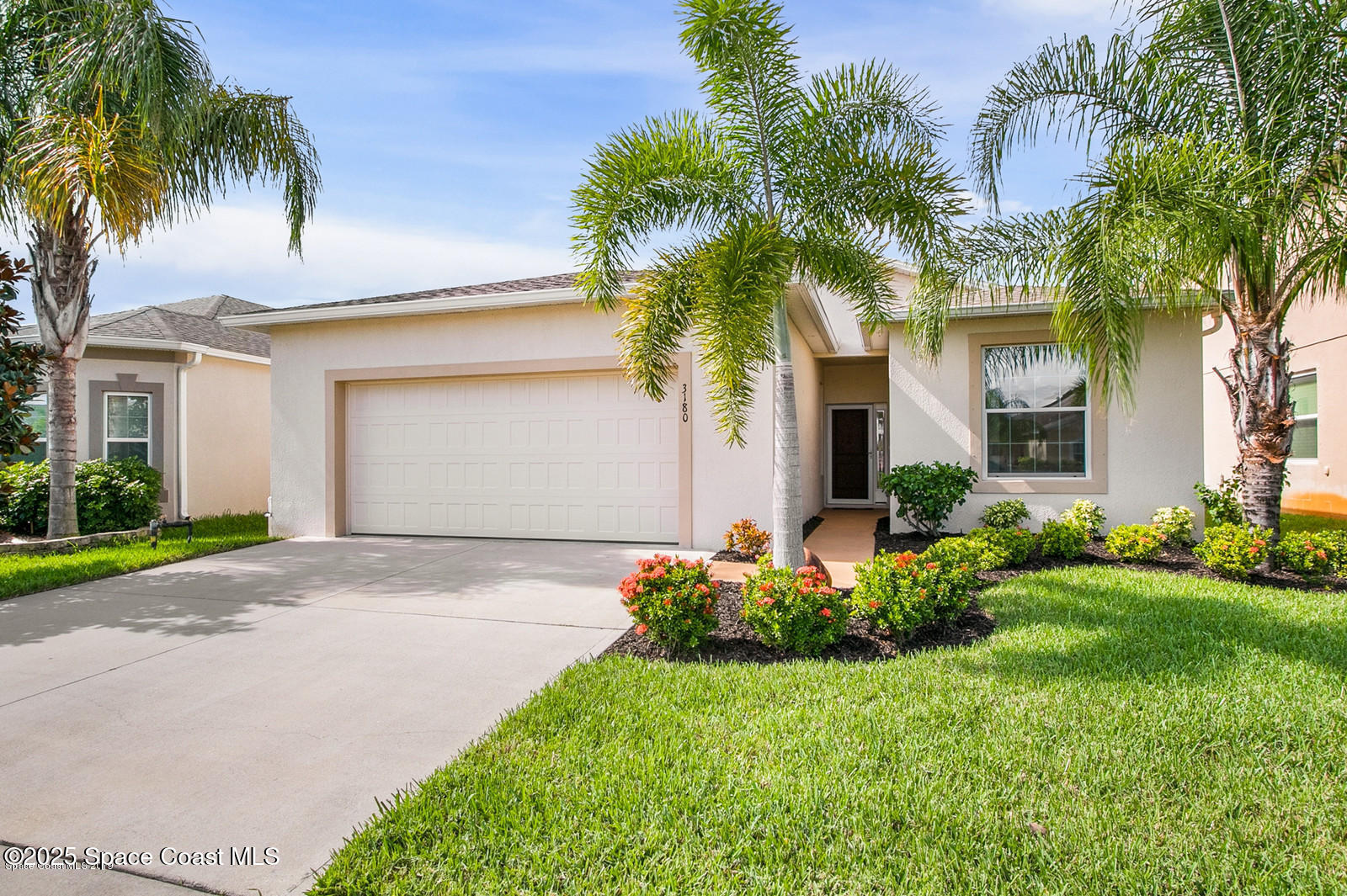 front view of house with a yard and palm trees