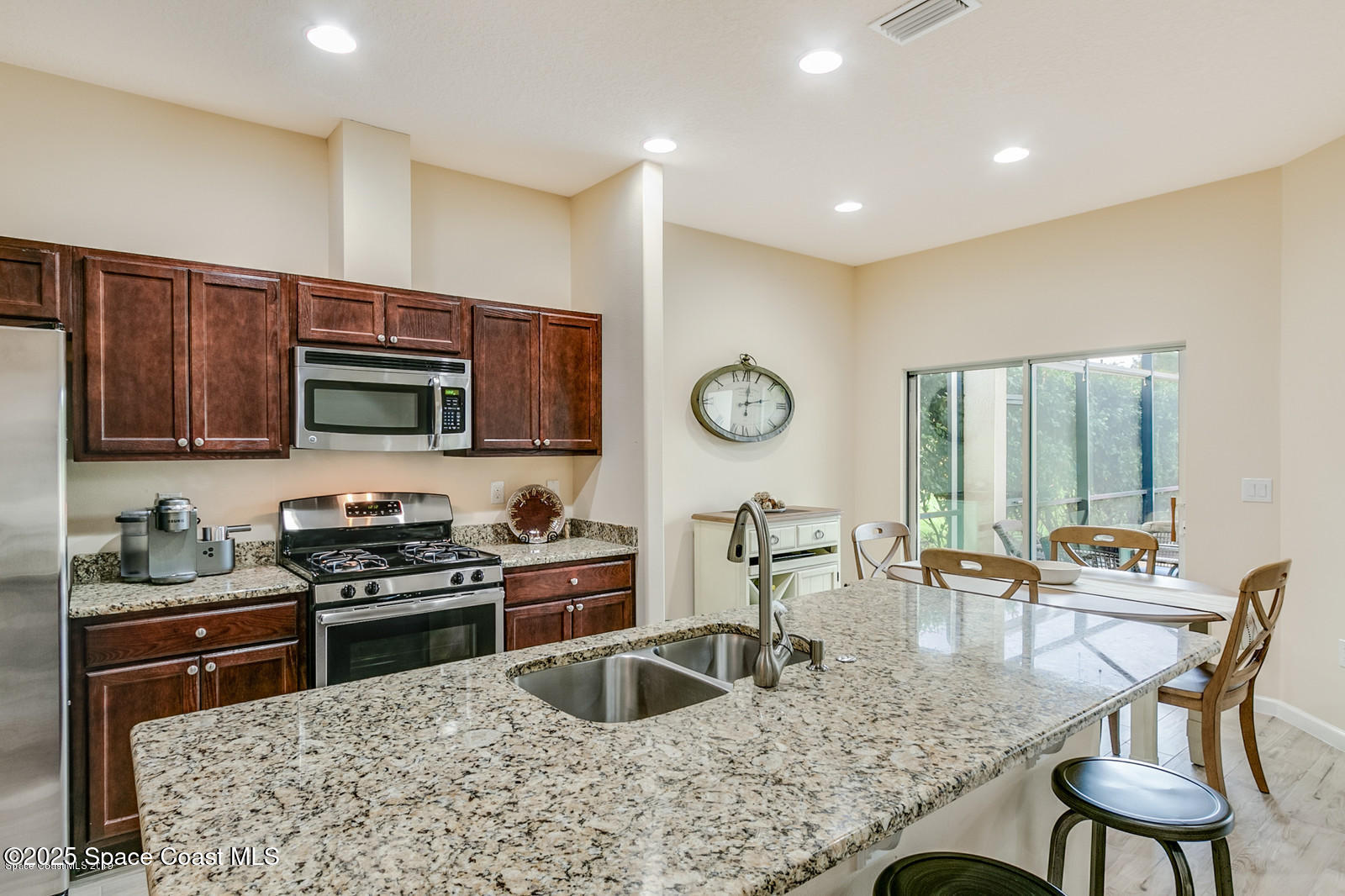 3180 Constellation Drive Melbourne, FL 32940 - Photo 6 of 18 a kitchen with stainless steel appliances granite countertop a stove top oven a sink a dining table and chairs