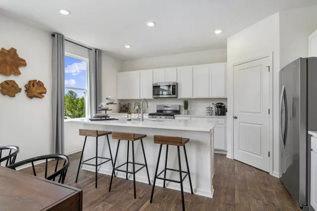 a kitchen with stainless steel appliances granite countertop a table chairs refrigerator and microwave